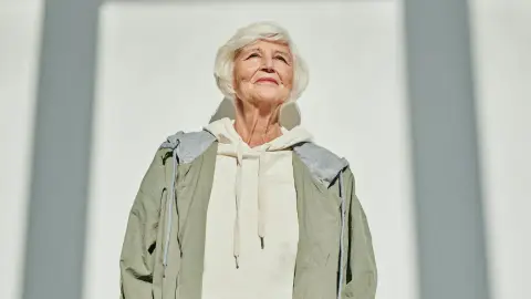 A confident older woman standing in sunlight