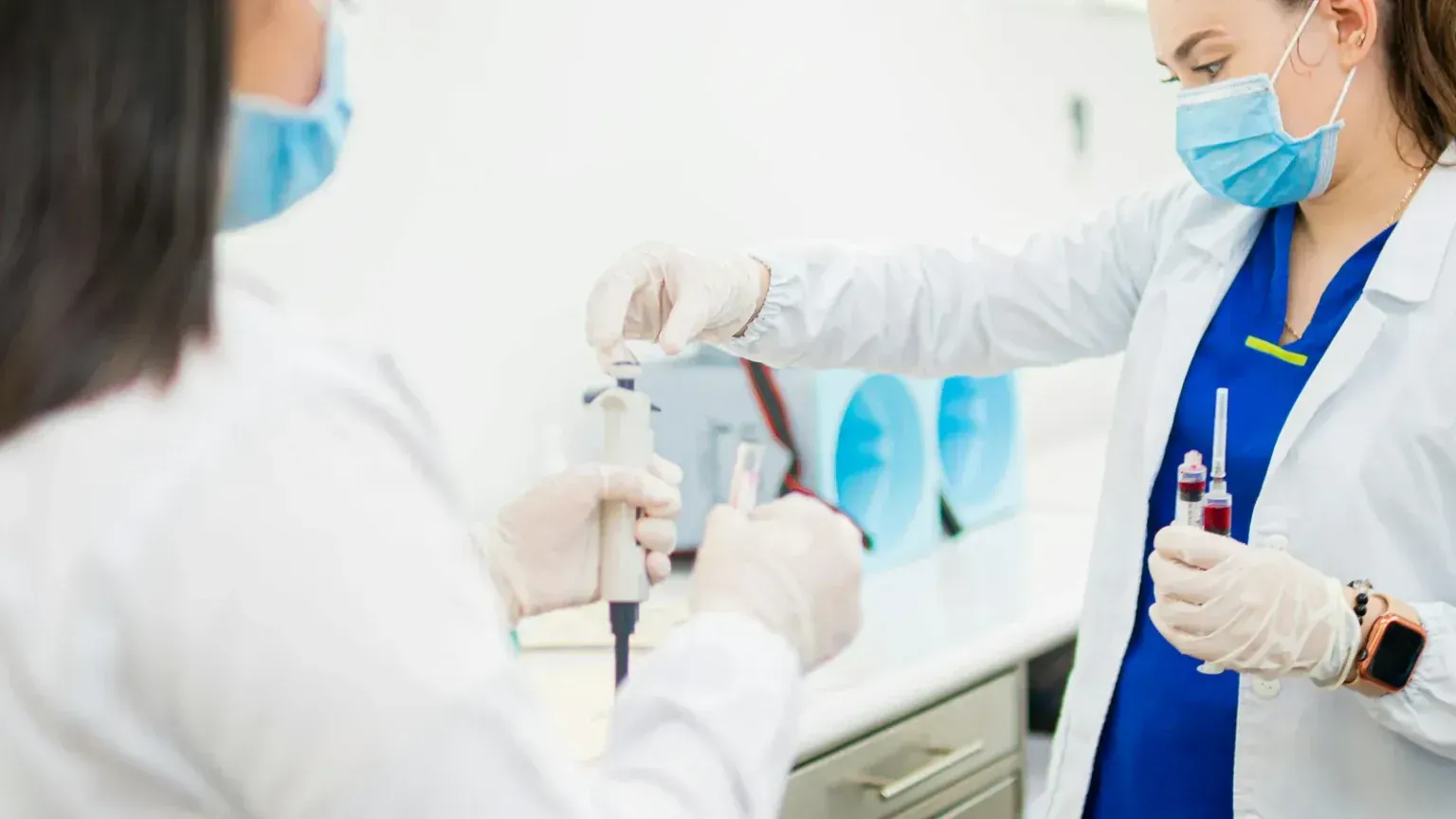 Two lab technicians handling blood sample tubes