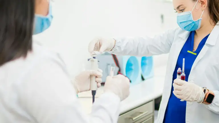 Two lab technicians handling blood sample tubes